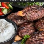 Spiced beef kebabs (kofte) with pita, tzatziki sauce, and a tomato cucumber salad.