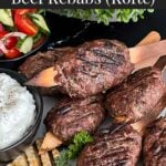 Spiced beef kebabs (kofte) with pita, tzatziki sauce, and a tomato cucumber salad.q