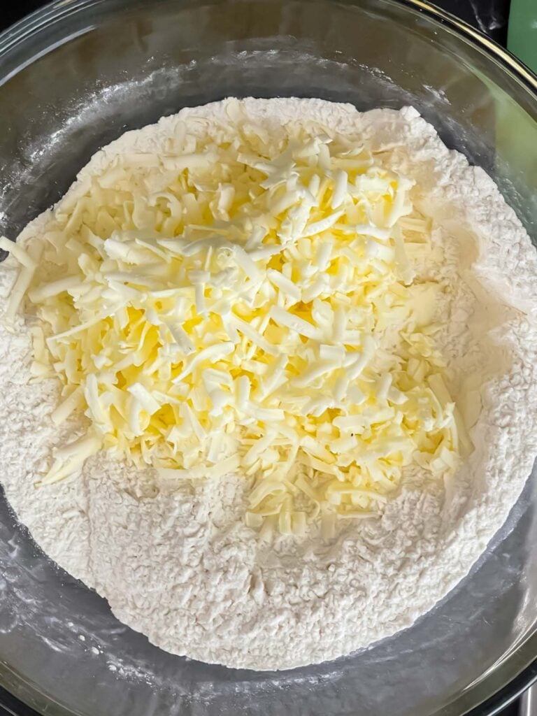 Butter added to dry ingredients in a glass bowl for strawberry scones.