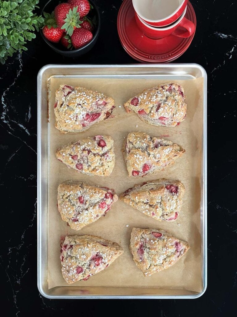Baked strawberry scones on a baking sheet.