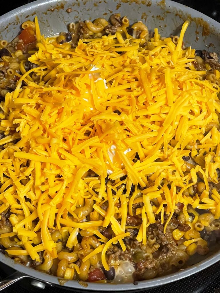 Adding cheese to ingredients in a skillet.