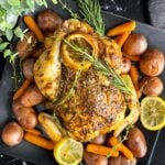 Slow cooker lemon herb whole chicken on a dark plate on a dark surface.