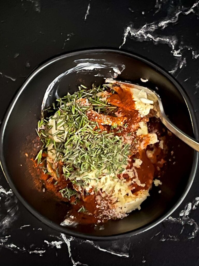 Compound butter ingredients in a dark bowl on a dark surface.