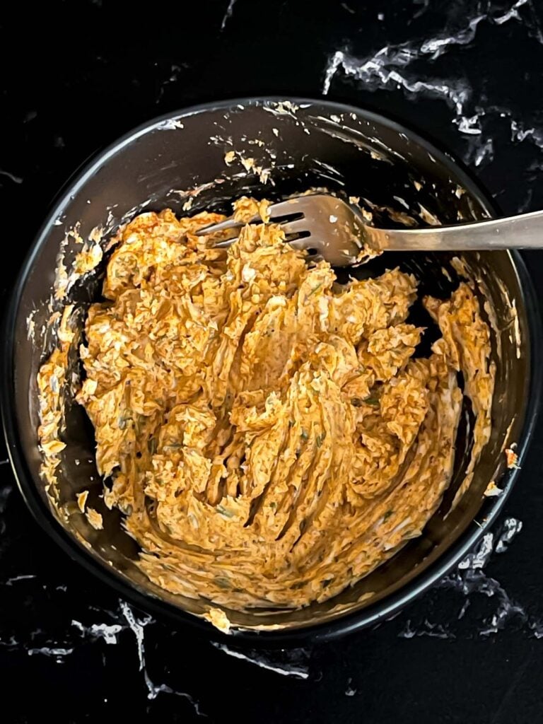 Lemon herb compound butter combined in a dark bowl on a dark surface.