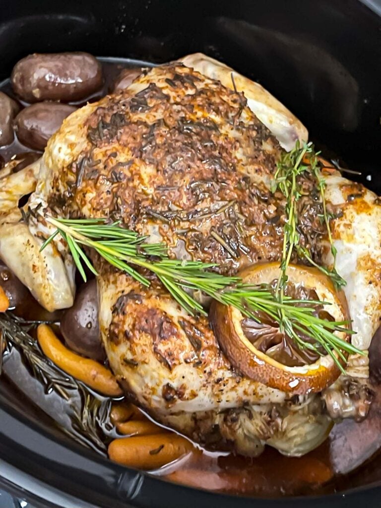 Cooked slow cooker lemon herb whole chicken in the crock pot.