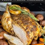 Slow cooker lemon herb whole chicken on a dark plate on a dark surface.