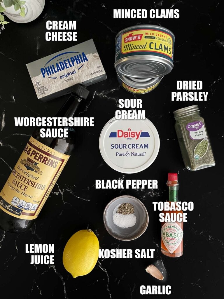 Clam dip recipe ingredients on a dark surface.