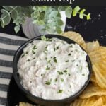 Clam dip in a dark bowl surrounded by kettle potato chips.
