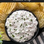 Clam dip in a dark bowl surrounded by kettle potato chips.