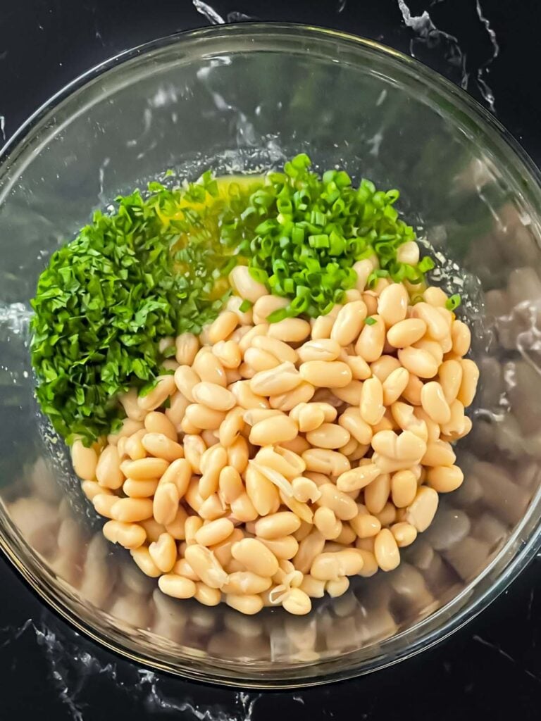 Ingredients for a lemon white bean salad in a glass bowl.
