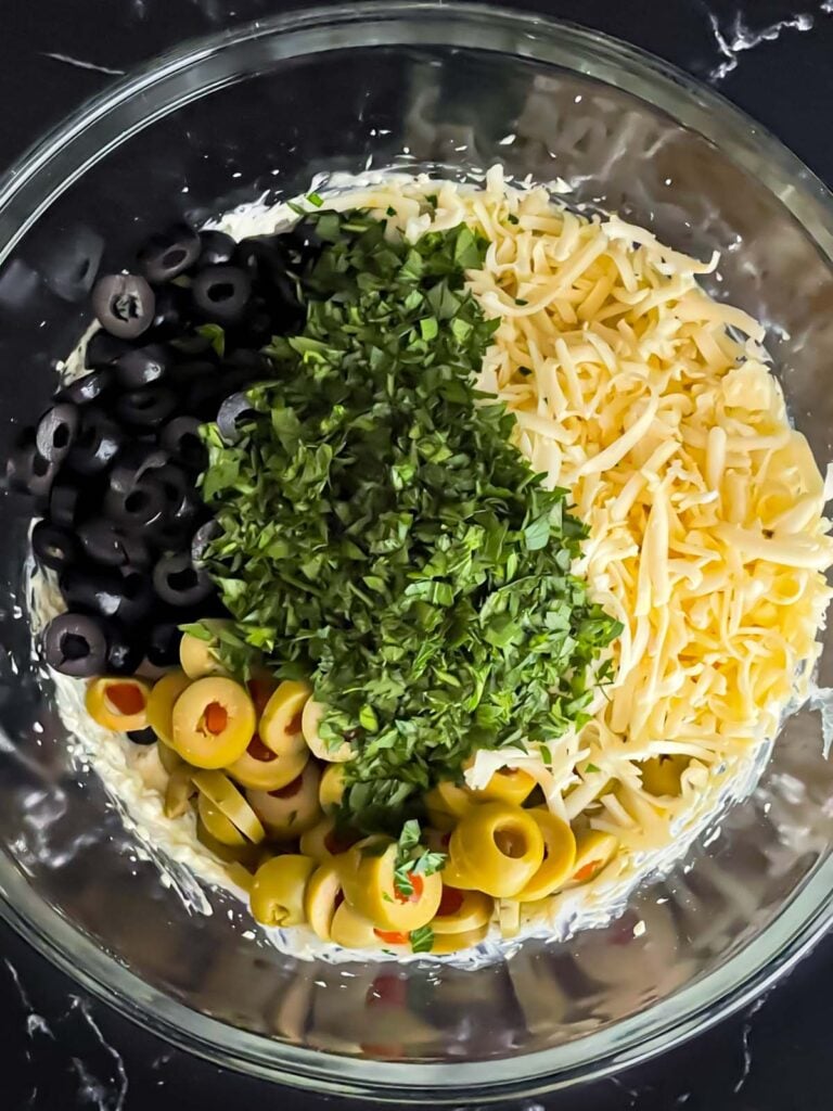 Olive cheese bread ingredients in a glass mixing bowl.