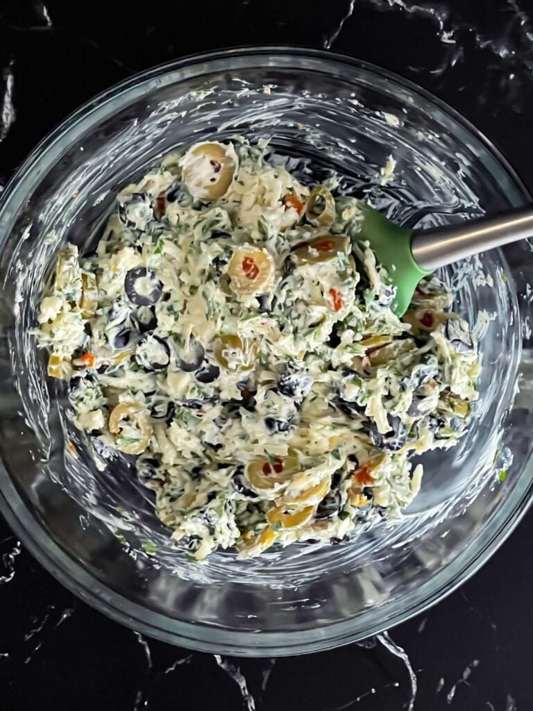 Olive cheese bread topping mixed together in a glass bowl.