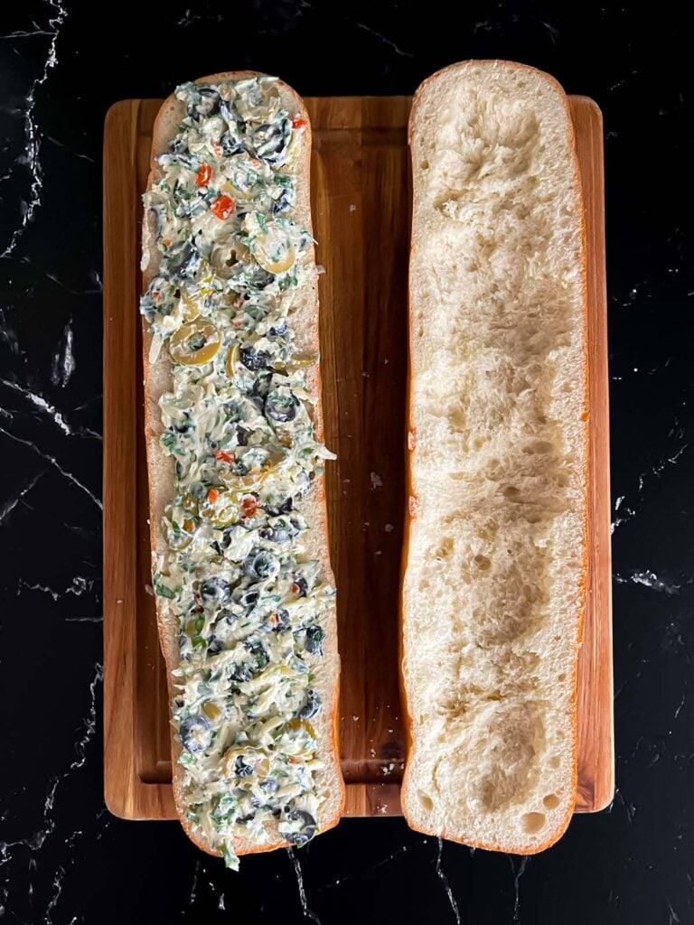 Olive cheese mixture spread inside half of the bread loaf.