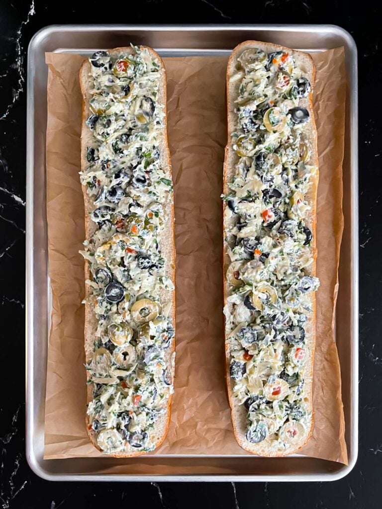 Unbaked olive cheese bread on a parchment paper lined baking sheet.