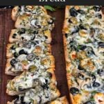 Olive cheese bread on a wooden cutting board.