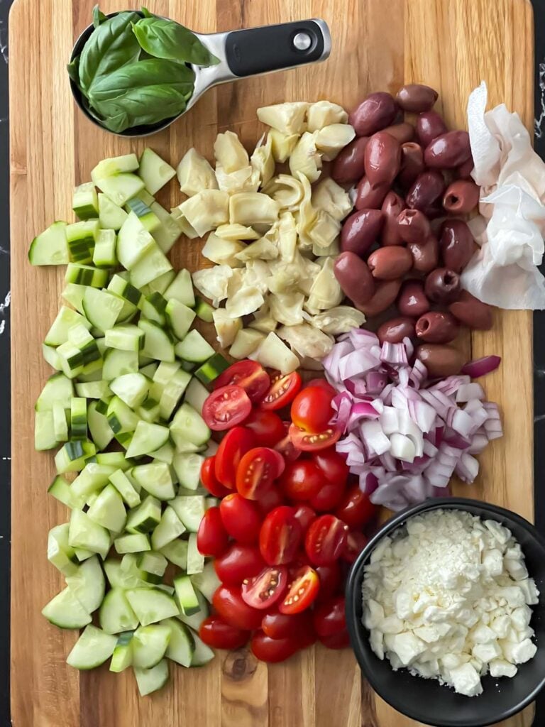 Vegetables for the tortellini pasta salad chopped on a wooden cutting board.