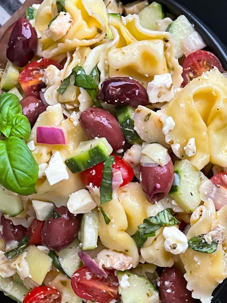 Tortellini pasta salad in a dark bowl.