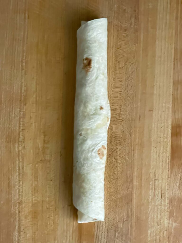 Veggie tortilla roll up on a wooden cutting board.