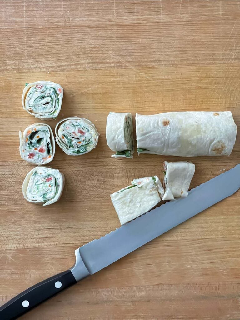 Sliced veggie tortilla roll ups on a wooden cutting board.
