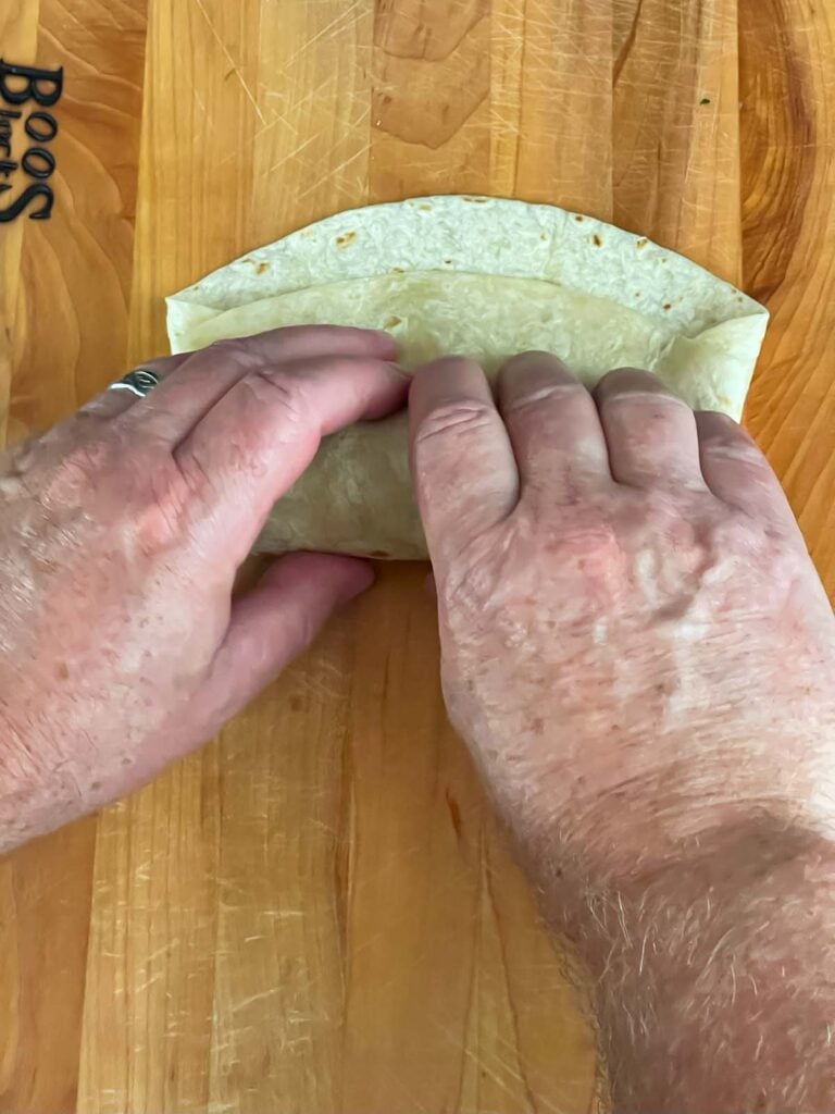 Wrapping the tortilla on a wooden board.