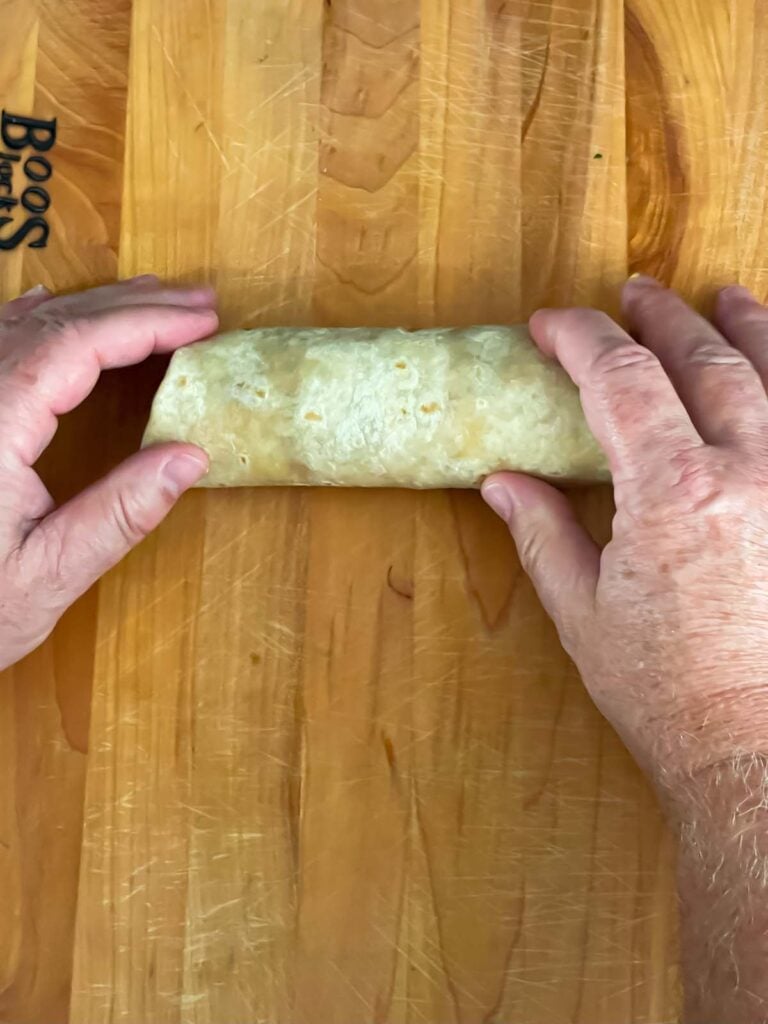Wrapped chimichango on a wooden board.