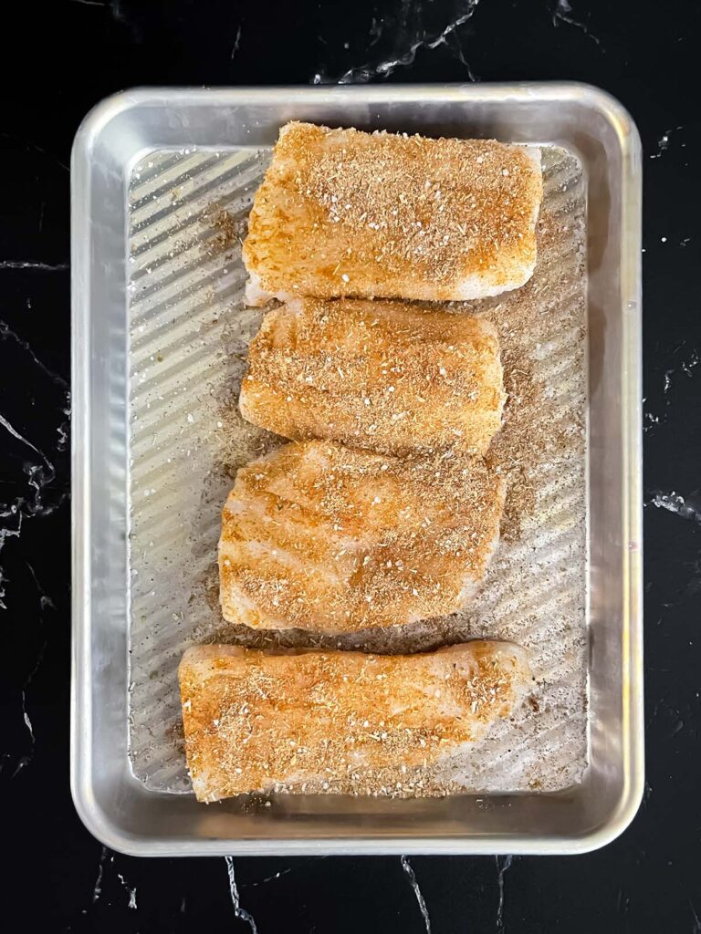Seasoned fish on a small prep pan.