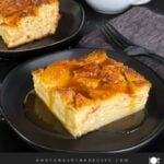 Bread pudding on a dark plate with a bourbon sauce drizzled over it.