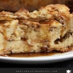 Bread pudding on a dark plate with a bourbon sauce drizzled over it.