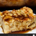 Bread pudding on a dark plate with a bourbon sauce drizzled over it.