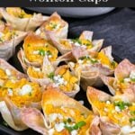 Buffalo chicken wontons garnished with chives and blue cheese crumbles on a dark plate.