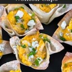 Buffalo chicken wontons garnished with chives and blue cheese crumbles on a dark plate.
