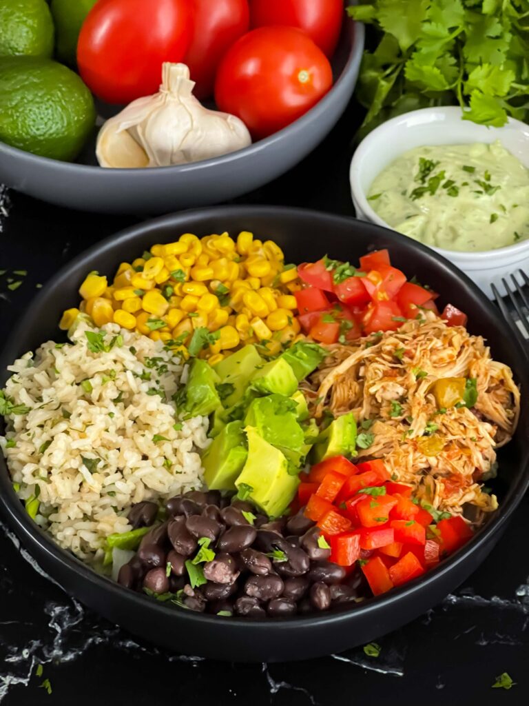 A chicken burrito bowl with an avocado sauce on a dark background.