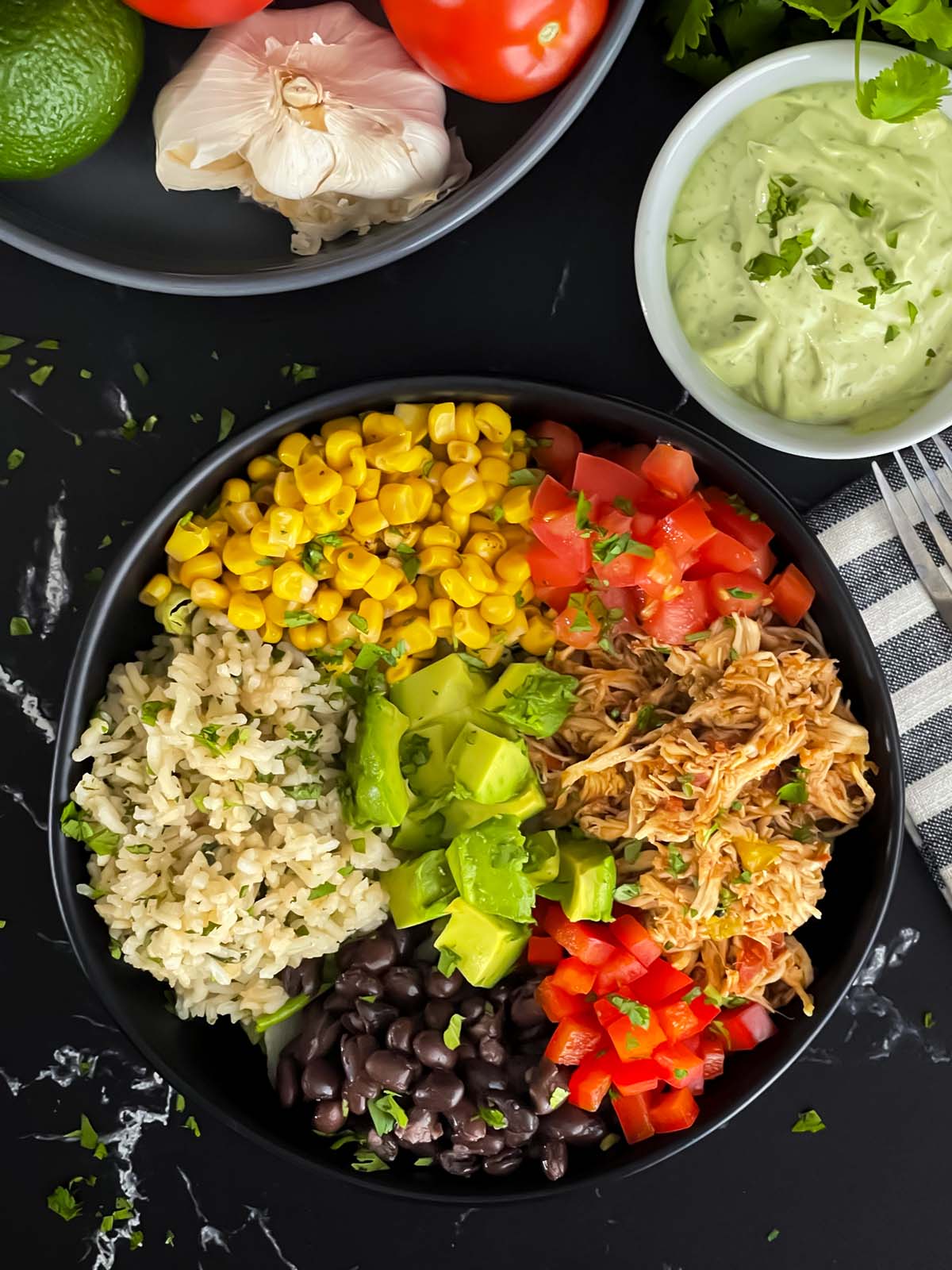A chicken burrito bowl with an avocado sauce on a dark background.