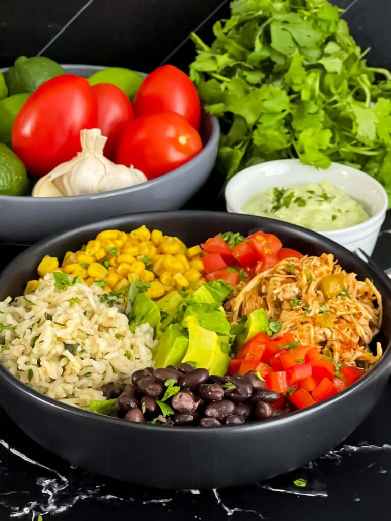 A chicken burrito bowl with an avocado sauce on a dark background.