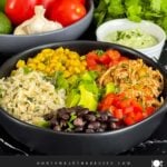 A chicken burrito bowl with an avocado sauce on a dark background.