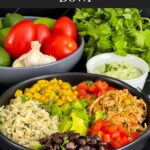 A chicken burrito bowl with an avocado sauce on a dark background.