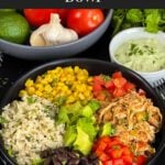 A chicken burrito bowl with an avocado sauce on a dark background.