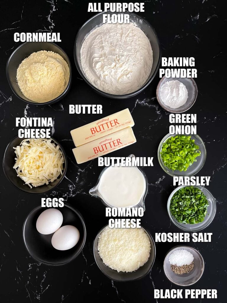 Herb and cheese muffins recipe ingredients on a dark surface.