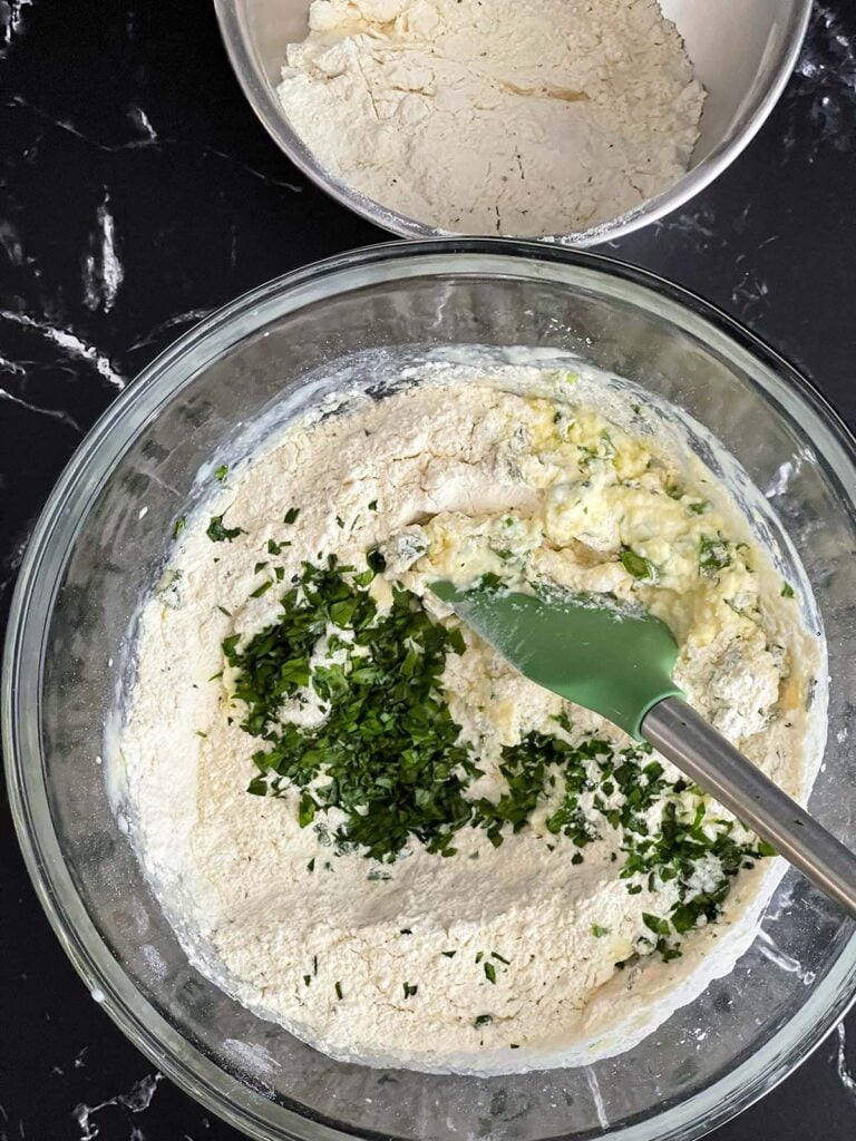 Dry ingredients and chopped herbs added to the wet ingredients for herb and cheese muffins.
