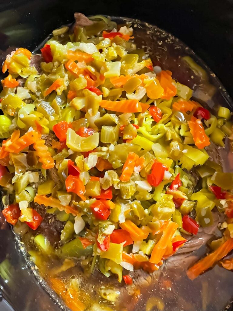 Pepperoncini and giardiniera over the roast in the slow cooker.