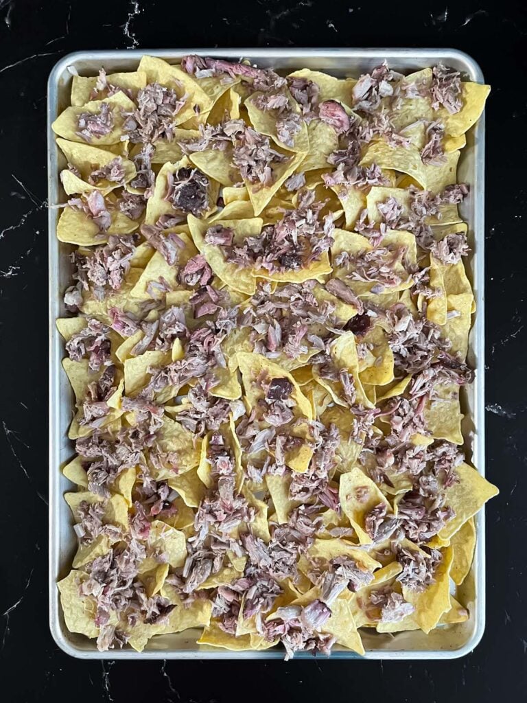 Tortilla chips with some smoked pork on top.
