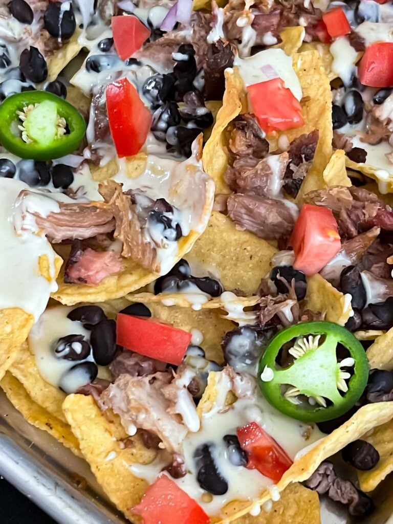 Pulled pork nachos with red onion, tomato, and jalapeno.