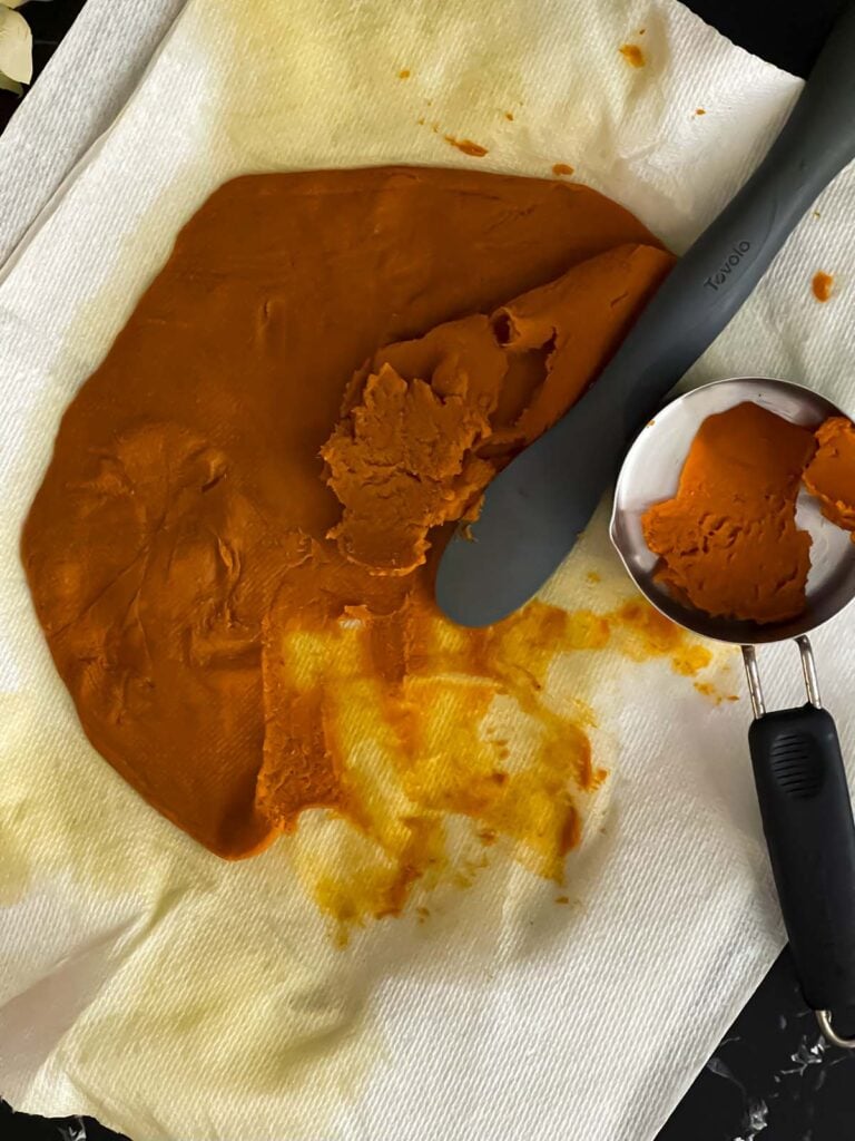 Paper towel drained pumpkin puree being placed in a measuring cup.