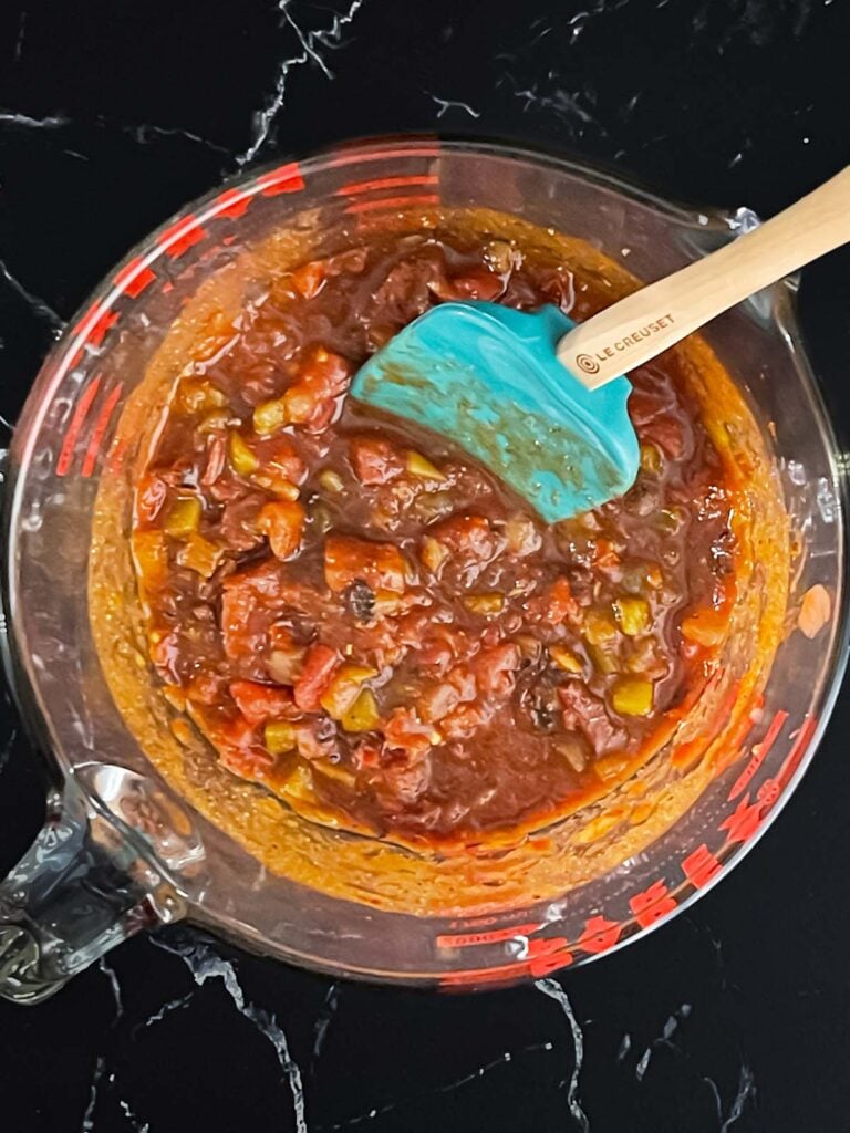 Tomatoes, green chilies, and seasonings combined in a large glass measuring cup for the slow cooker Mexican chicken recipe.