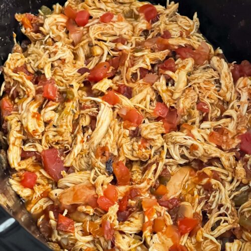 Shredded Mexican chicken in the crock of a slow cooker.