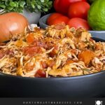 Slow cooker Mexican chicken in a dark bowl on a dark surface.
