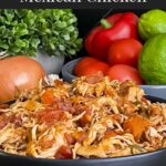 Slow cooker Mexican chicken in a dark bowl on a dark surface.