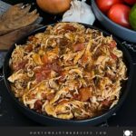 Slow cooker Mexican chicken in a dark bowl on a dark surface.
