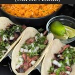 Flank steak street tacos with rice, chips, and garnish on a dark background.