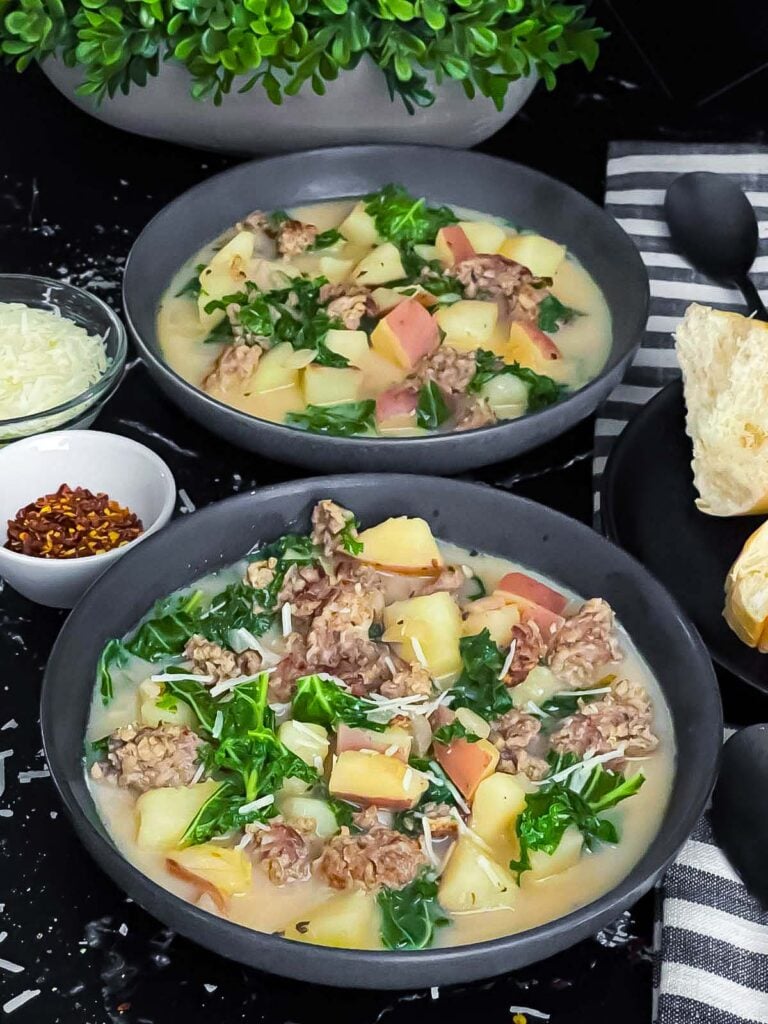 Sausage, potato and kale soup (Zuppa Toscana) in dark bowls on a dark surface.
